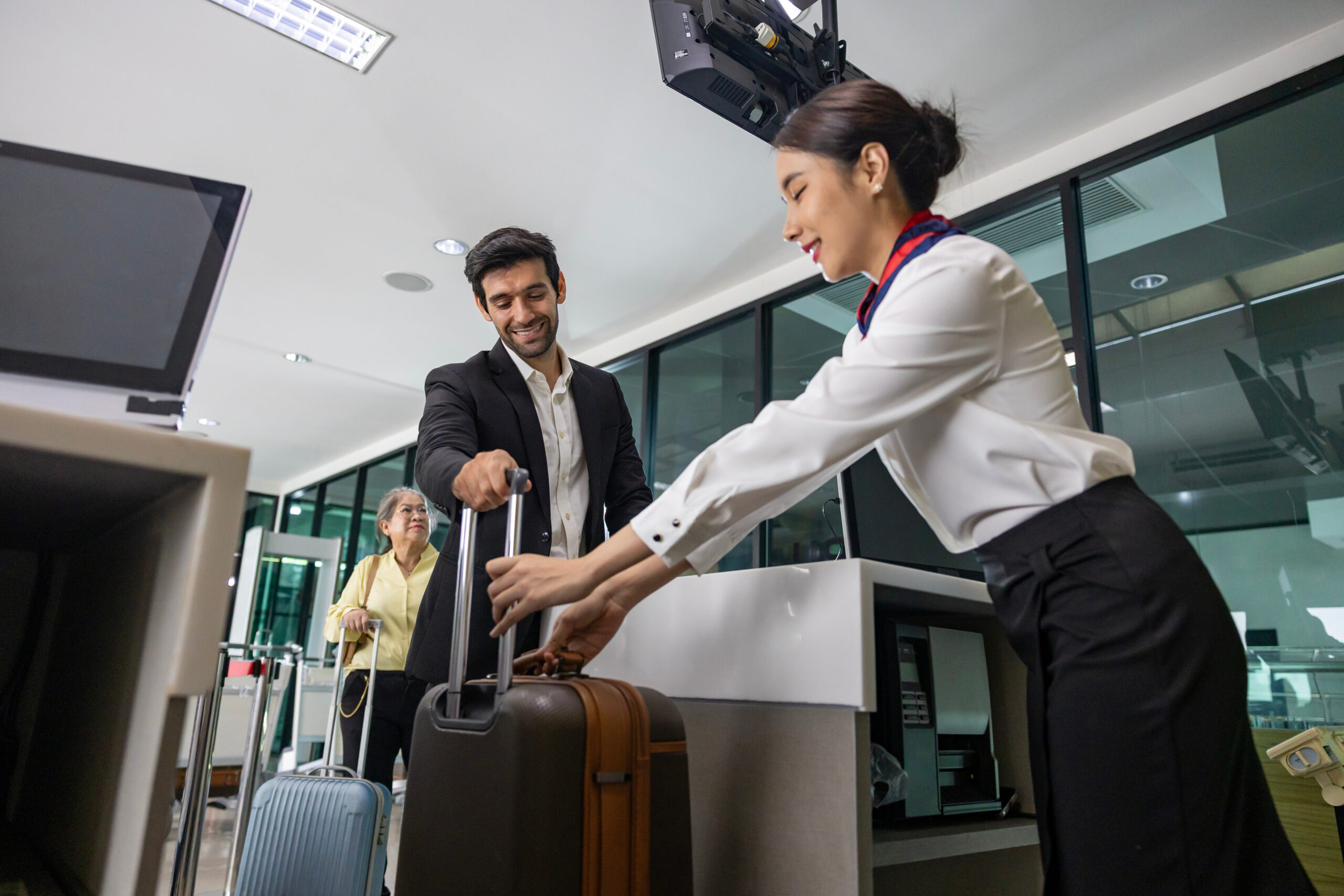 Caucasian businessman passenger is checking in big baggage bag to airline ground crew at departure gate into the airplane for measuring weight before boarding to plane
